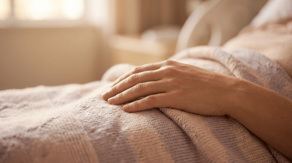 A mother's hand gently resting on a soft baby blanket in warm golden light, evoking the peaceful first hours of recovery